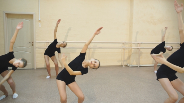 Group Of Four Young Ballerinas Standing In Row And Practicing Ballet