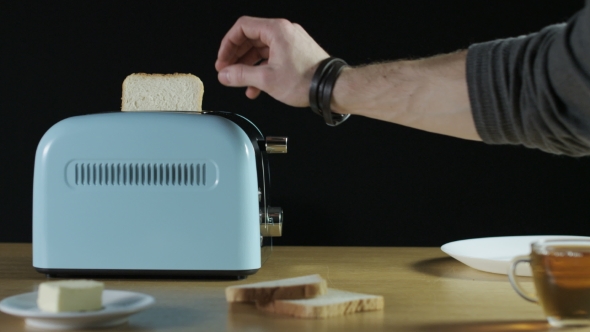 Man Puts Two Loaves Of Bread Into An Electric Toaster