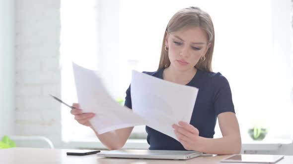 Woman Reading Reports While Sitting in Office