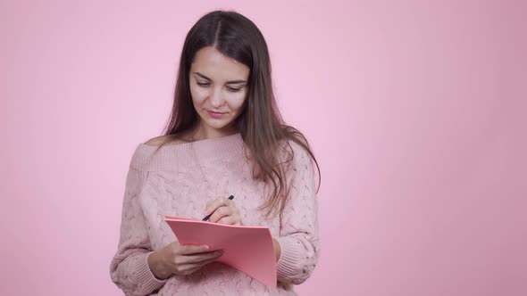 Young Beautiful Woman Is Writing Down a List of Necessary Purchases or To-dos