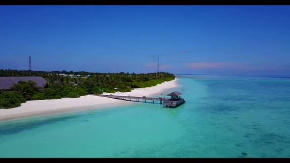 Aerial drone shot landscape of idyllic coastline beach break by blue water with white sand backgroun