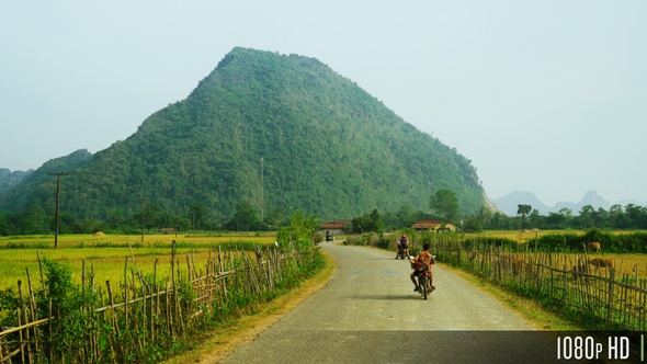 Remote Countryside Road in Southeast Asia with Motorcycle Traffic Rice Fields and Mountains