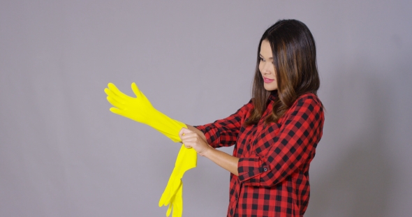 Young Housewife Putting On Rubber Gloves