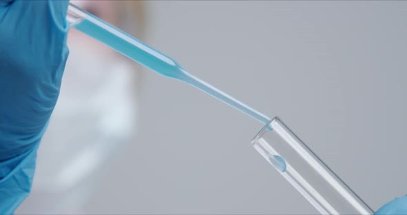 Technician Carefully Drips the Solution From the Pipette Into Glass Tubes. alt