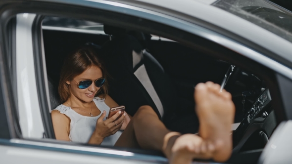 Young Woman In Sunglasses Resting In The Car And Sending Messages