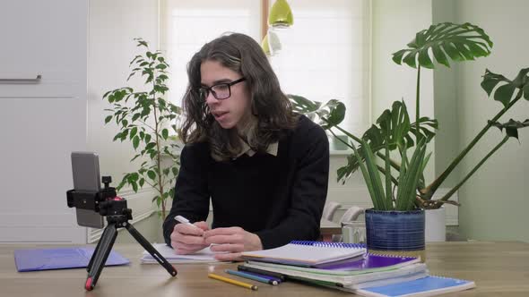 Male Teenage High School Student at Home Looking at Smartphone Camera Studying Online