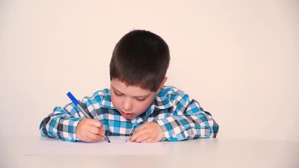 A 4Yearold Boy Draws Circles on Paper with a Blue Marker