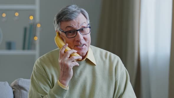 Portrait Funny Grandpa Retired Pretends to Speak Banana Like on Phone Humorous Conversation Old Man