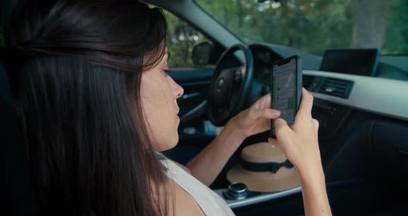 Young Woman Sit on Vehicle Interior Using Mobile Phone on Summer Road Trip