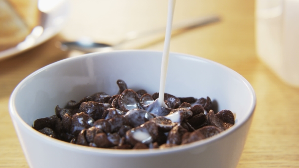 Pouring Milk Into a Bowl With Chocolate Flakes