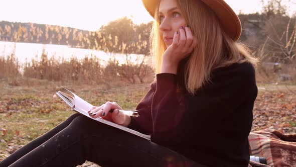 Slow Motion Caucasian Blonde Woman with Beige Hat in Black Sweater Write on Notebook in the