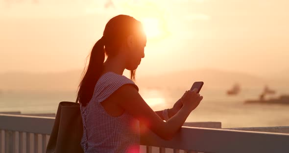 Woman use of mobile phone under sunset