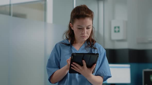 Close Up of Medical Assistant Looking at Tablet Screen with Information