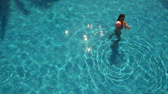 Young Woman Playing With Ball On Swimming Pool