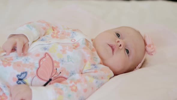 The Baby is Lying on the Bed and Smiling at the Camera Close Up View