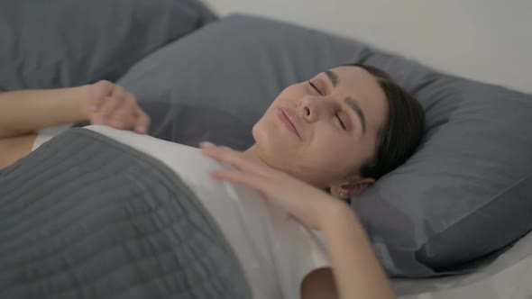 Hispanic Woman Waking up from Sleep in Bed