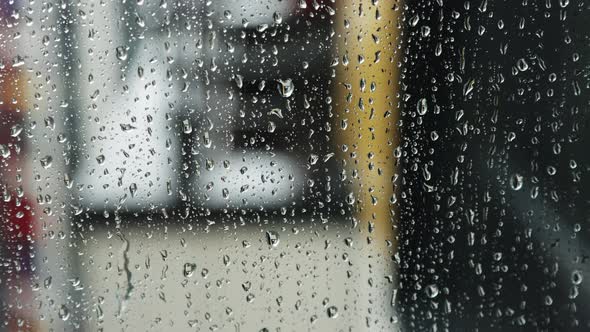 Raindrops run down the window pane on a rainy day alt