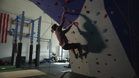 Young man climbing wall in gym