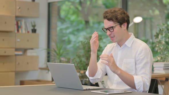 Young Man Reacting to Loss While Using Laptop in Modern Office