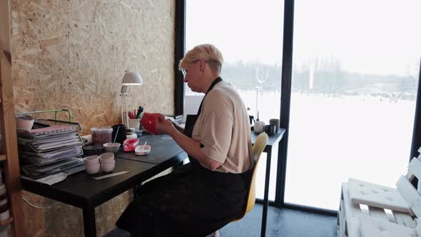 An Elderly Woman Painting Ceramic Mug with Red Color