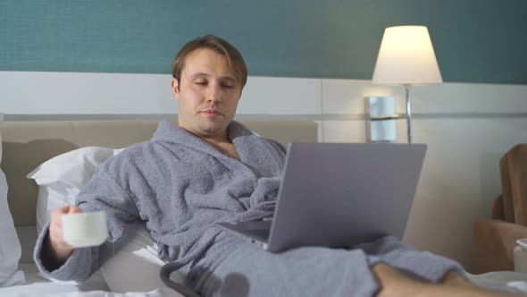 Man working on laptop while lying in bed.