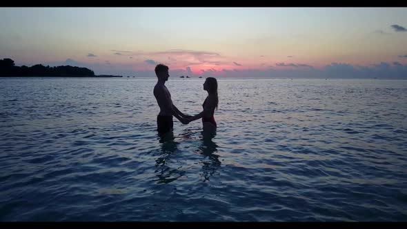 Two lovers engaged on luxury shore beach break by turquoise ocean and white sandy background of the 