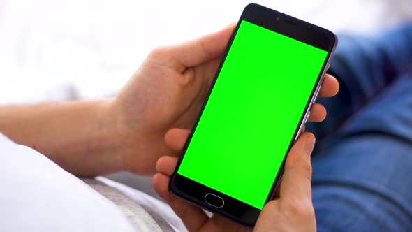 Black Smartphone with Green Screen for Chroma Key Compositing the Hands of a Man on Laptop