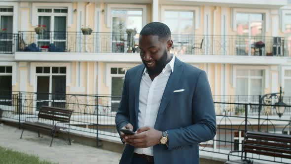 Smiling Afro Man Texting Message Outdoors