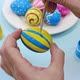 Happy Easter Close Up. A white man paints blue lines on a yellow Easter egg with a brush - VideoHive Item for Sale