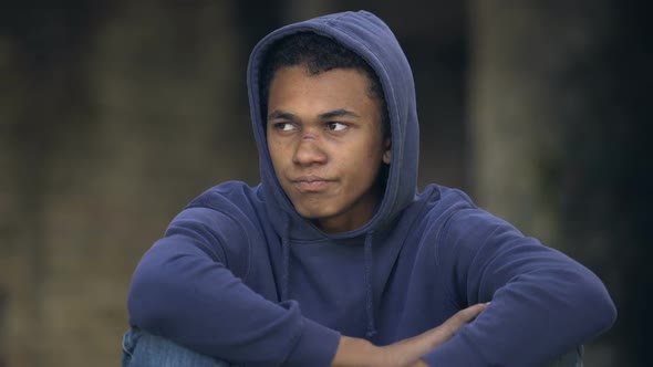 Depressed Male Teen in Hoodie With Face Wound Drinking Alcohol Outdoors, Puberty