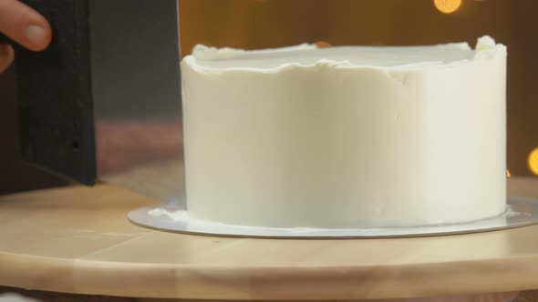 Closeup of the Pastry Chef Smoothing the Cream on the Cake with a Spatula