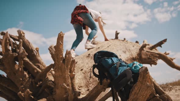 Young Adventurer, Woman Tourist Climbing on the Tree Trunk in the Desert. Focus on the Backpack in