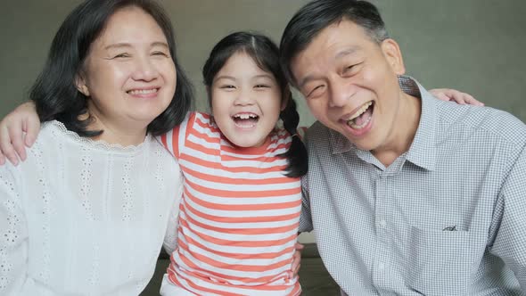 asian senior grandparent and grand daughter sitting on bed hugging lovely together