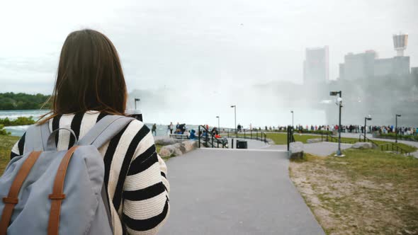 Camera Follows Thoughtful Local Woman Walking Towards Crowded Observation Deck at Mighty Niagara