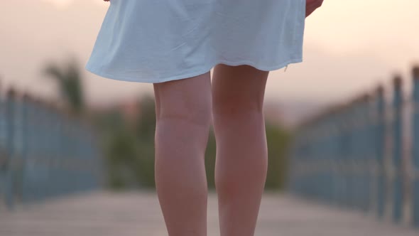 Closeup of Young Woman in White Dress Walking on Long Pier in the Evening