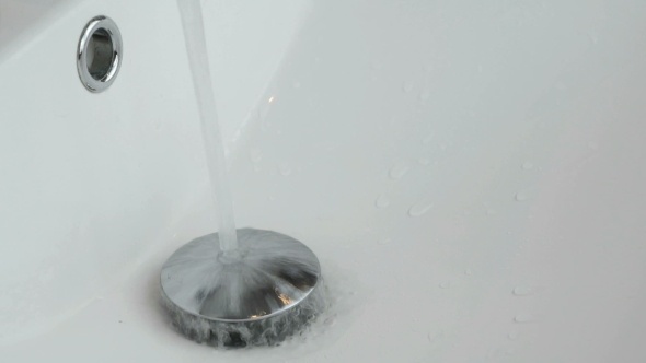 The Process Of Draining Water Into The White Sink