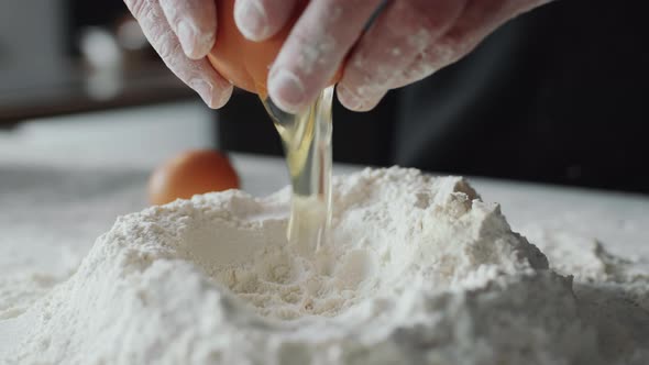 Baker Adding Egg to Flour Mound