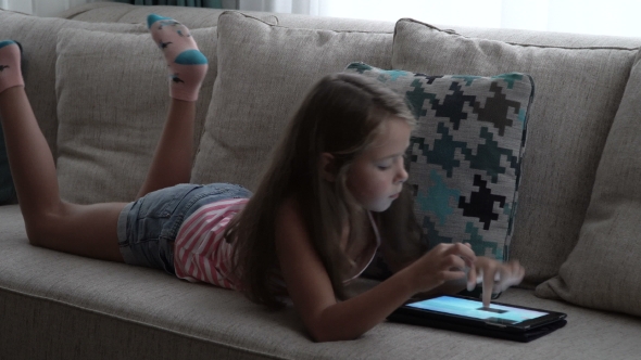 Little Girl Playing a Game on Tablet at Home