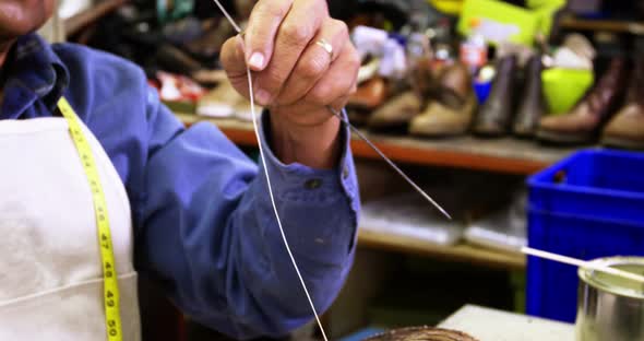 Cobbler putting thread in the needle