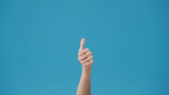 Young woman hand showing thumb up sign with fingers isolated over blue background in studio.