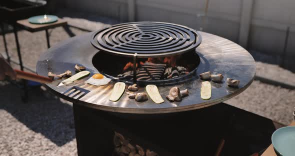 Man cooking breakfast for son. Fried eggs, cabbage, mushroom grilled on bbq grill.