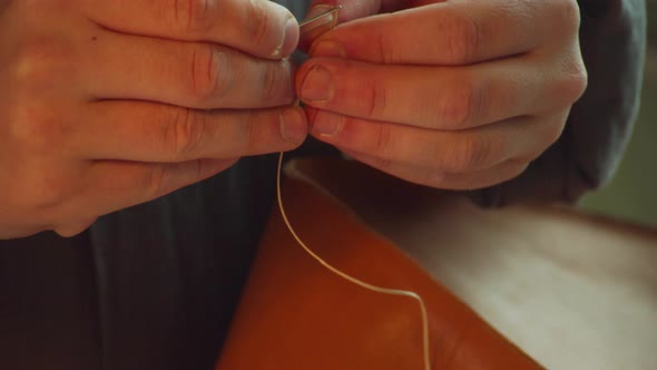 The Hands of an Experienced Tailor Thread a Tailor's Needle To Make a Bag Made of Genuine Leather.