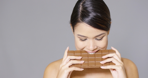 Pretty Woman Biting Into a Bar Of Chocolate
