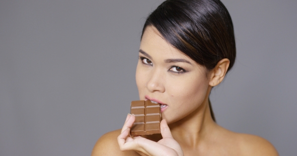Sensual Young Woman Nibbling On a Chocolate Bar