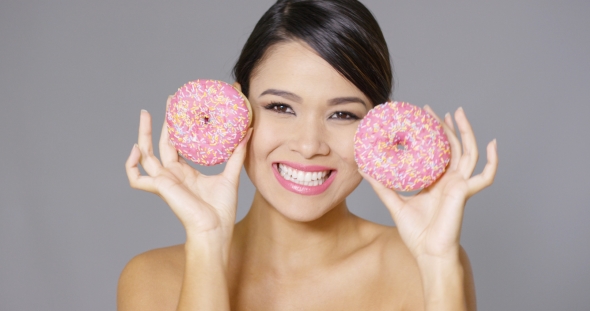 Laughing Woman Holding Two Pink Donuts To Her Eyes