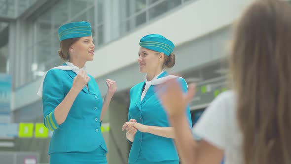 Blurred Caucasian Little Girl Waving To Beautiful Stewardesses in Blue Uniform. Two Confident Slim