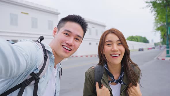 Asian couple backpacker use mobile phone selfie, take picture in city.