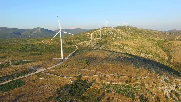 Aerial view of windmills with rotating blades on a sunny day