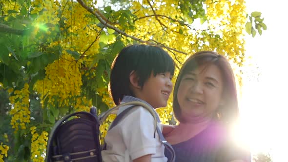 Asian Mother Holding Her Son While Walking In The Park , Back To School Concept