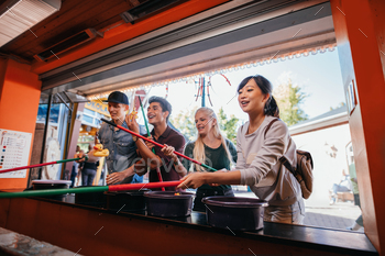 in amusement park. Multiracial friends playing arcade game.